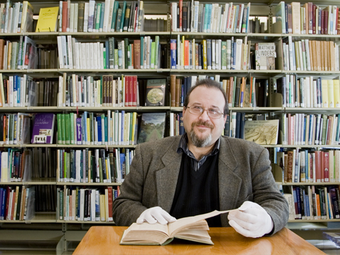 Librarian with an old book, bookshelves behind