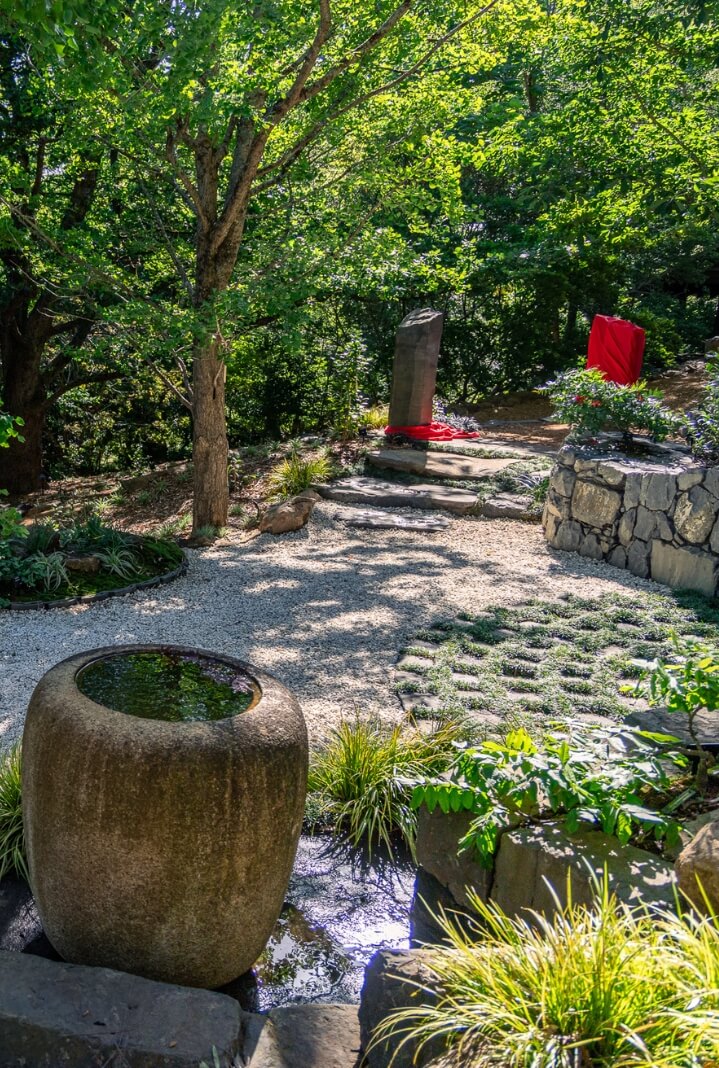 Japanese-styled pebbled, shady path with traditional stone and wood water features