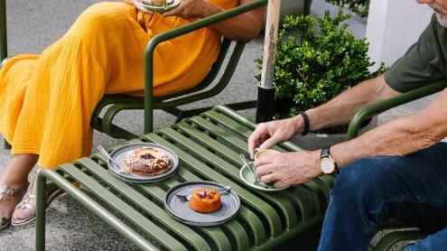 Two people dining on a patio with pastries and coffee